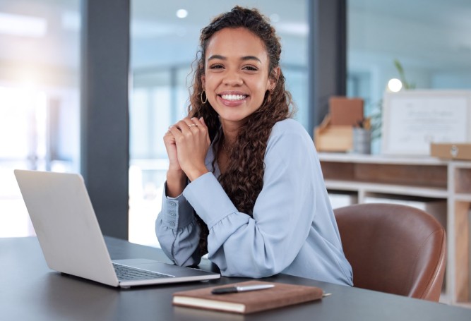 Young woman in front of a laptop smiling